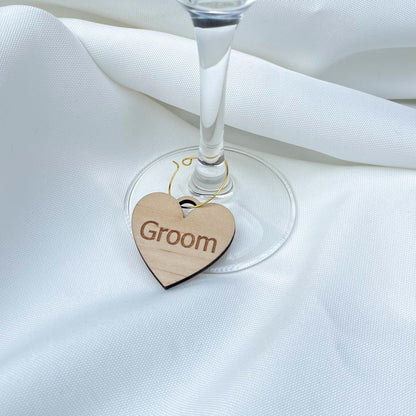 Heart-shaped wooden personalized wine charms tag with Groom text hanging on wine glass stem