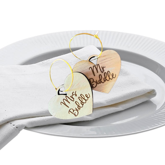 Heart-shaped personalized wine charms with Mr and Mrs Biddle wooden tags on white napkin